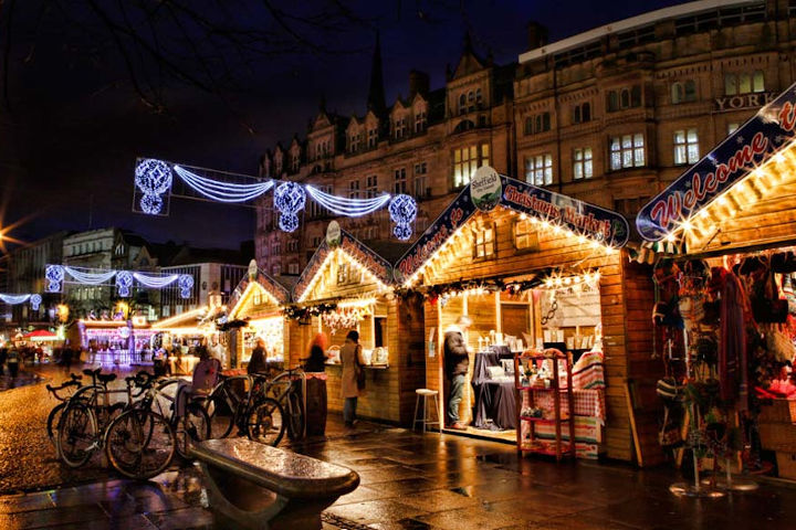 A bustling Christmas market scene with wooden stalls and festive lights on Fargate in Sheffield
